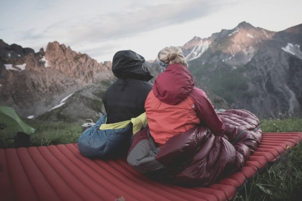 a couple of people sitting on top of a red blanket