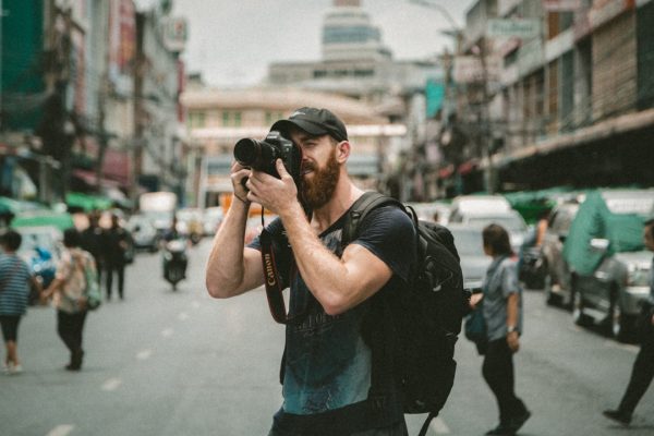 shallow focus photography of man using a DSLR camera