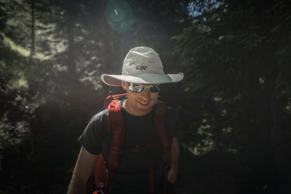a man wearing a hat and sunglasses in the woods