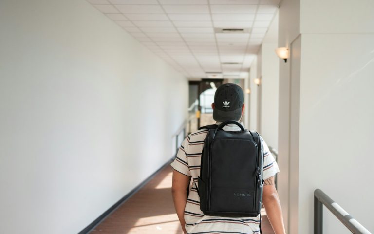 Professional carrying a work backpack through an office hallway