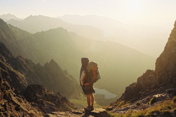 climber standing on rock near overlooking view of mountain at daytime