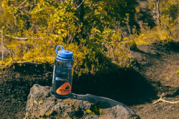 Blue water bottle resting on a rock outdoors.