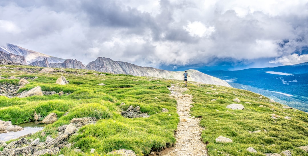 Two hikers with backpacks walking along a trail toward snow-capped mountains