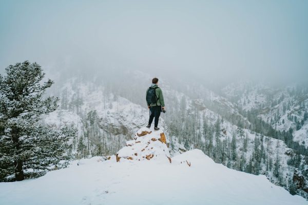 person at peak of mountain carrying red backpack