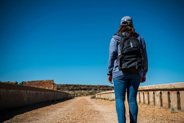 Woman with backpack walking on a dirt road