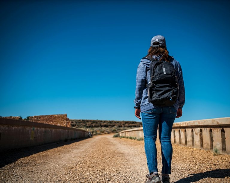 Woman with backpack walking on a dirt road